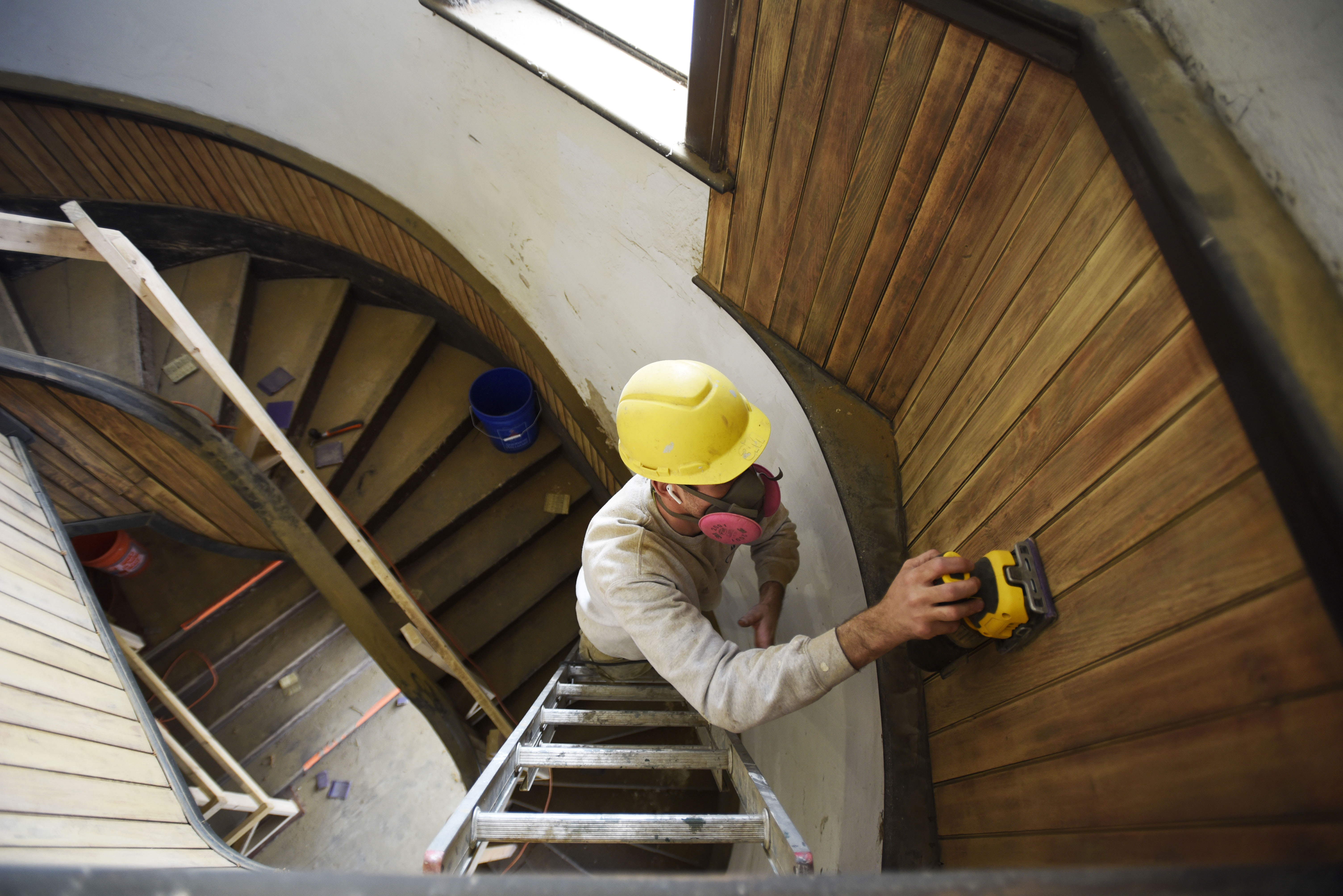 A construction worker refinishes original wood in a stairwell at Universal Preservation Hall in Saratoga Tuesday, April 9, 2019.